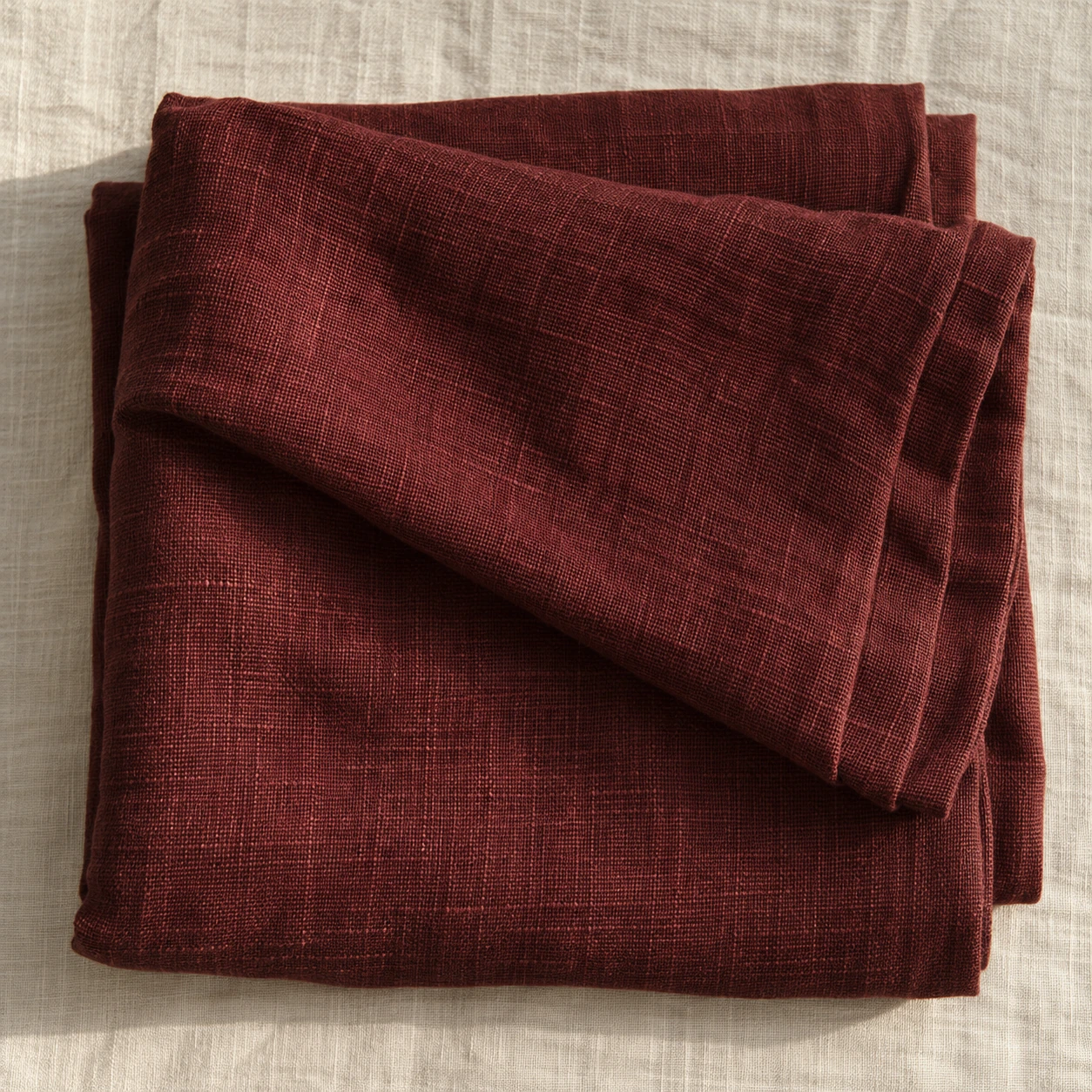 Folded oxblood linen, a deep wine red, the weave visible.