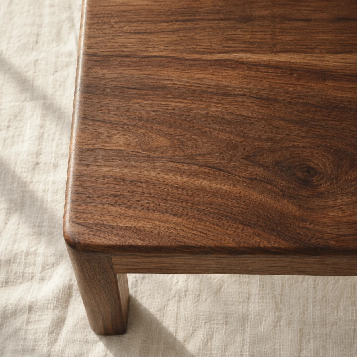The corner of an oiled walnut table, the grain running across the frame.