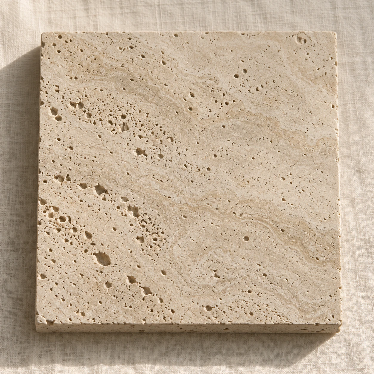 A cream travertine slab with its natural pores and cut edge.