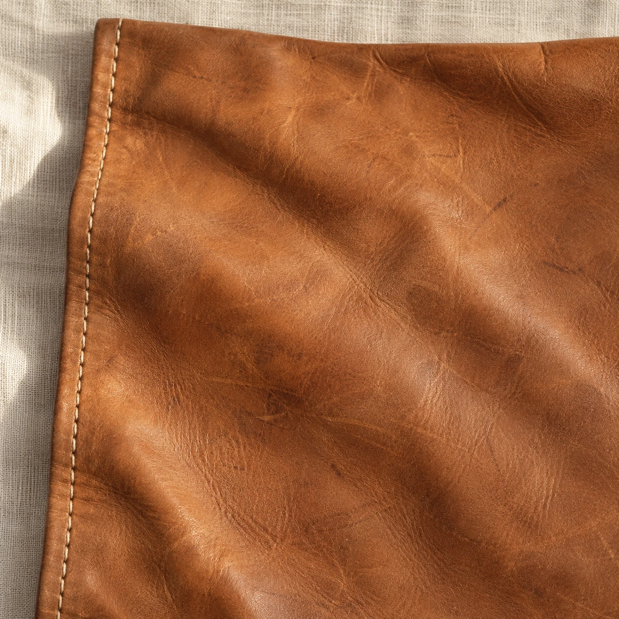 Tan leather with use marks and a row of stitching.