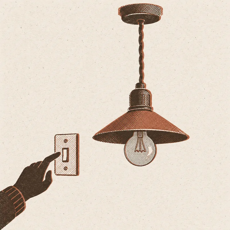 A finger reaching for a wall light switch beside a pendant lamp with a bare bulb hanging from a cord in the ceiling.