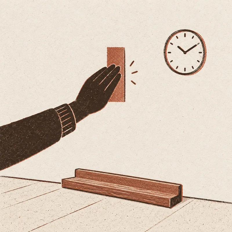 A hand pressing an adhesive strip against a wall, a round wall clock nearby, and an empty wooden picture ledge waiting on the floor below.