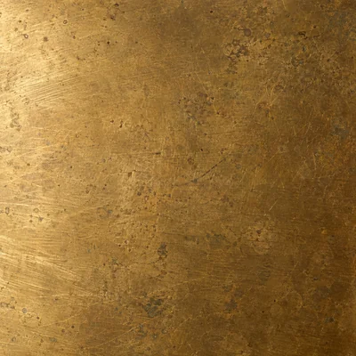 The same brass after four years: uneven warm patina, dark in the recesses, bright where fingers rub, two small dents.