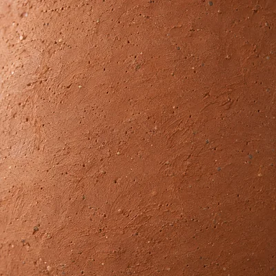 The same terracotta after four years: a chalky pale bloom, a darker water stain, one chipped edge showing lighter clay.