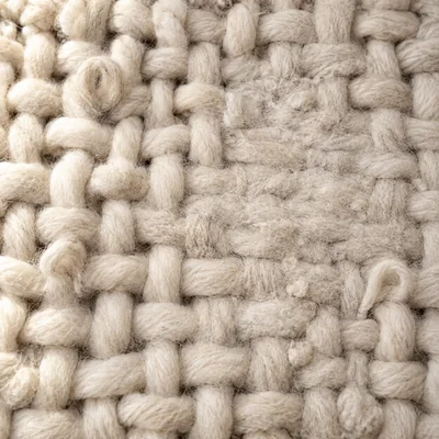 The same cream wool after four years: small pills, a few fibers pulled into loops, one flattened patch.